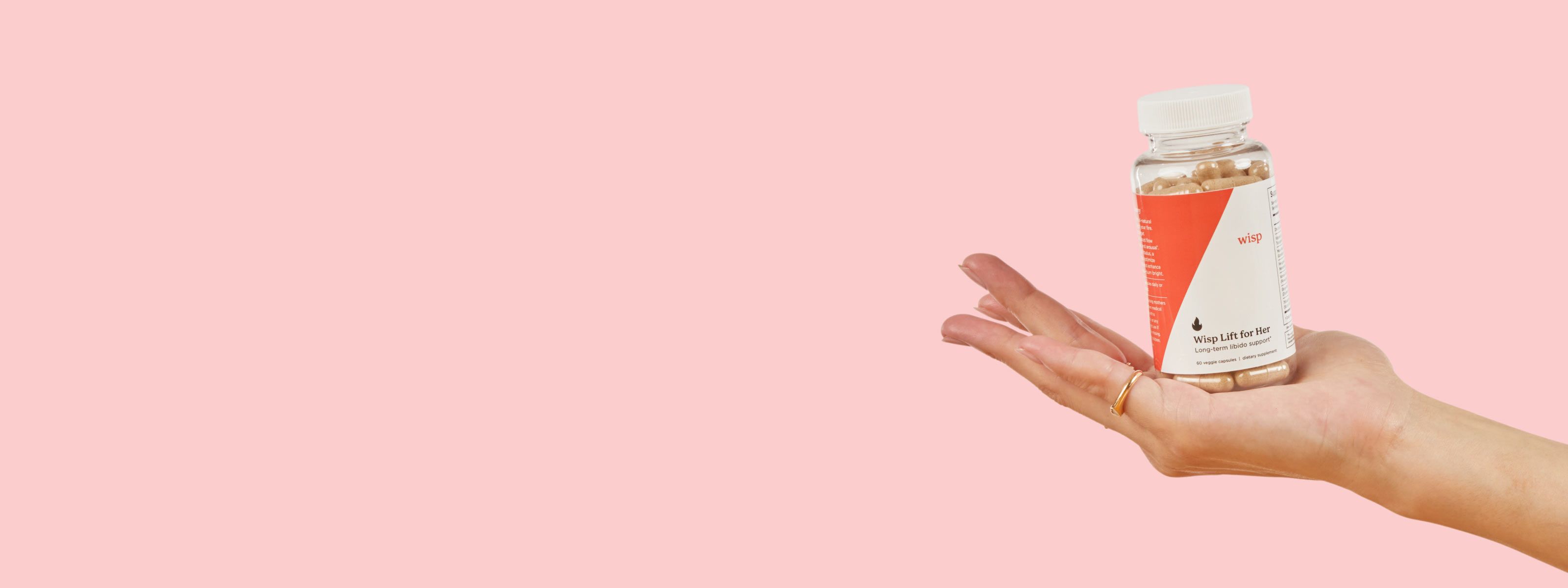 Woman's hand holding Wisp Lift for Her Libido Supplements on a pink background