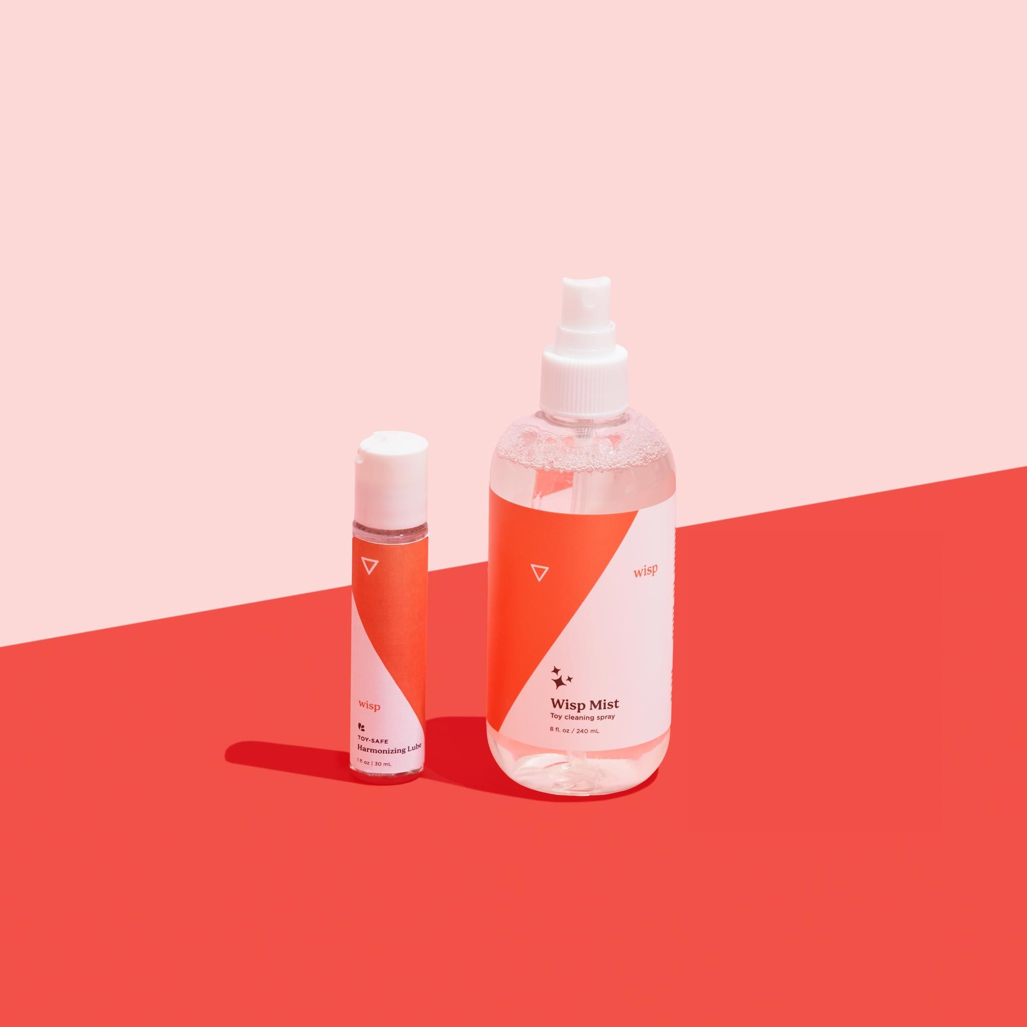 Wisp Mist and Wisp Harmonizing Lube on a red surface with a pink background