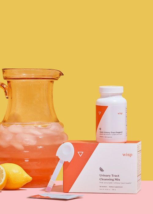 A pitcher of pink lemonade next two Wisp's Urinary Tract Duo on a pinks surface with a yellow background