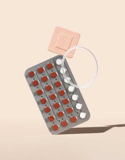 A birth control packet, patch, and ring balanced on a cream surface