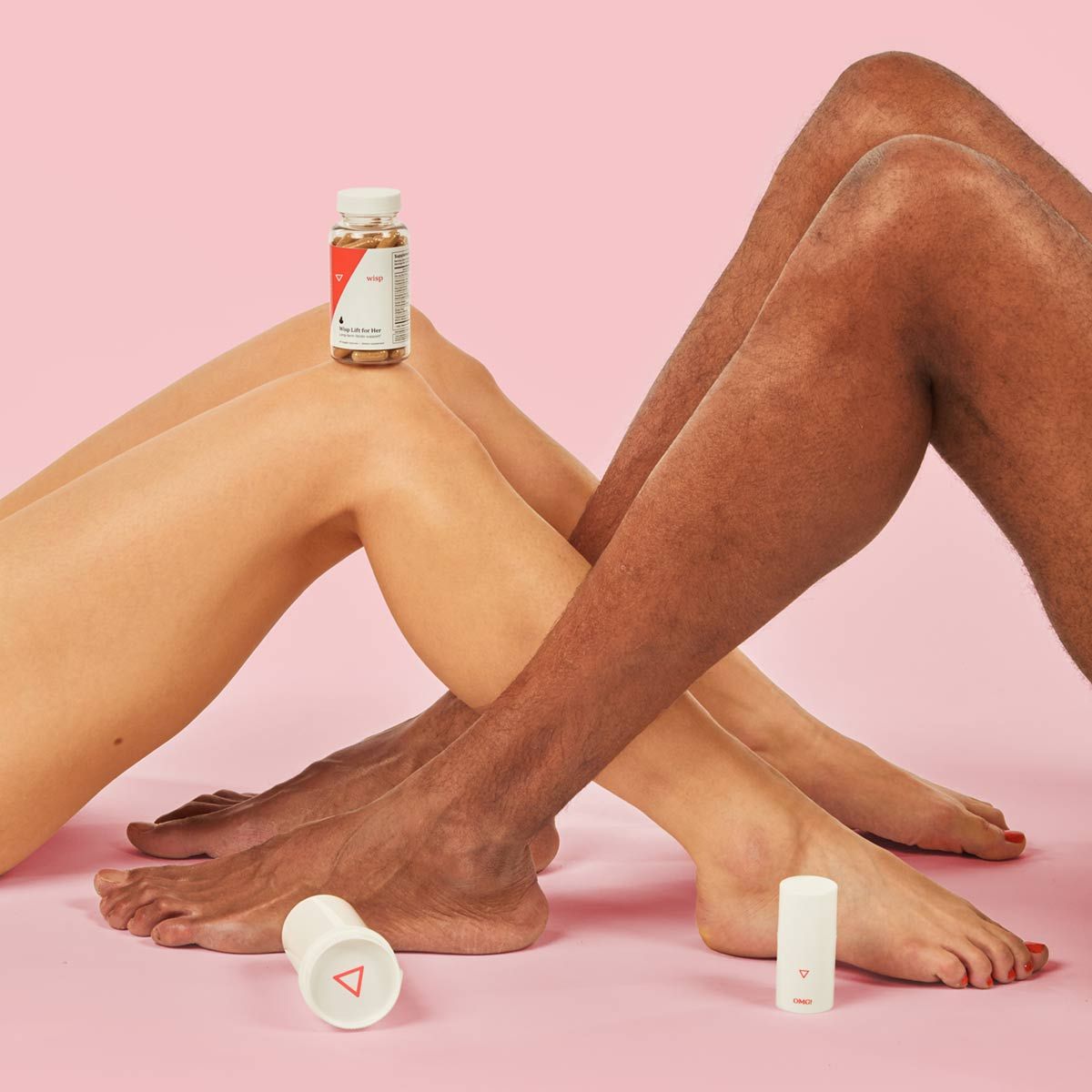 A woman and man's legs intertwined on a pink background, surrounded by Wisp Intimate Care products