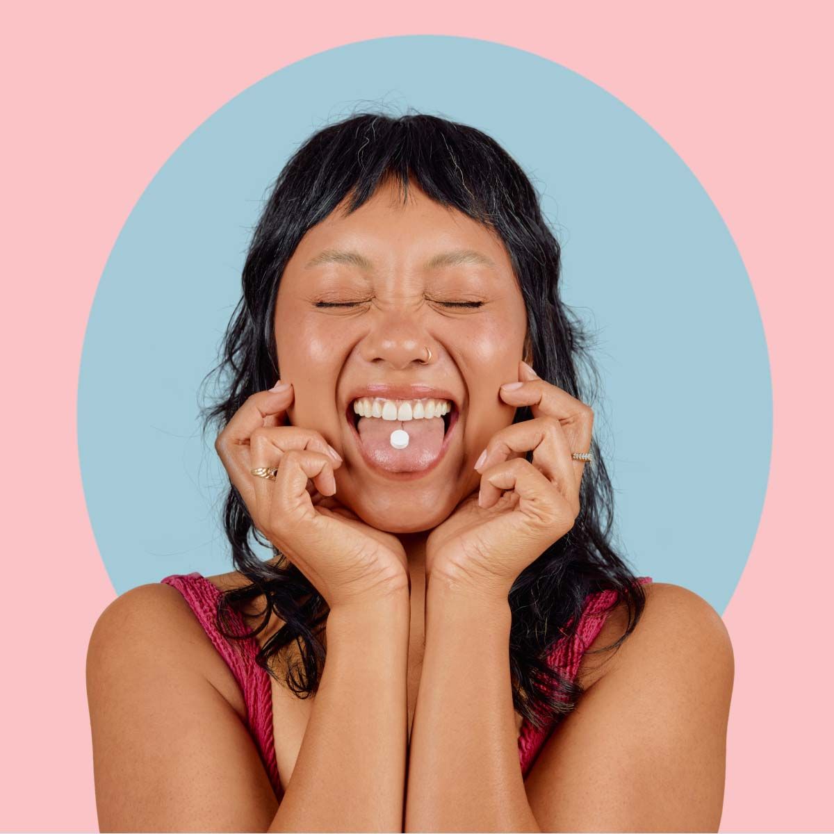 A pretty woman smiling and sticking her tongue out with a Wisp Basic Probiotics pill on it