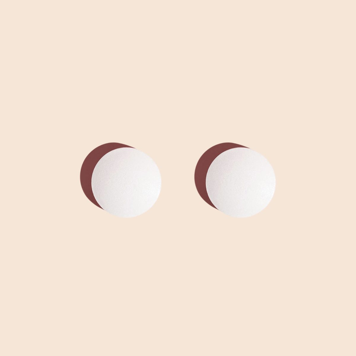 Two probiotic pills for women's health on a cream background