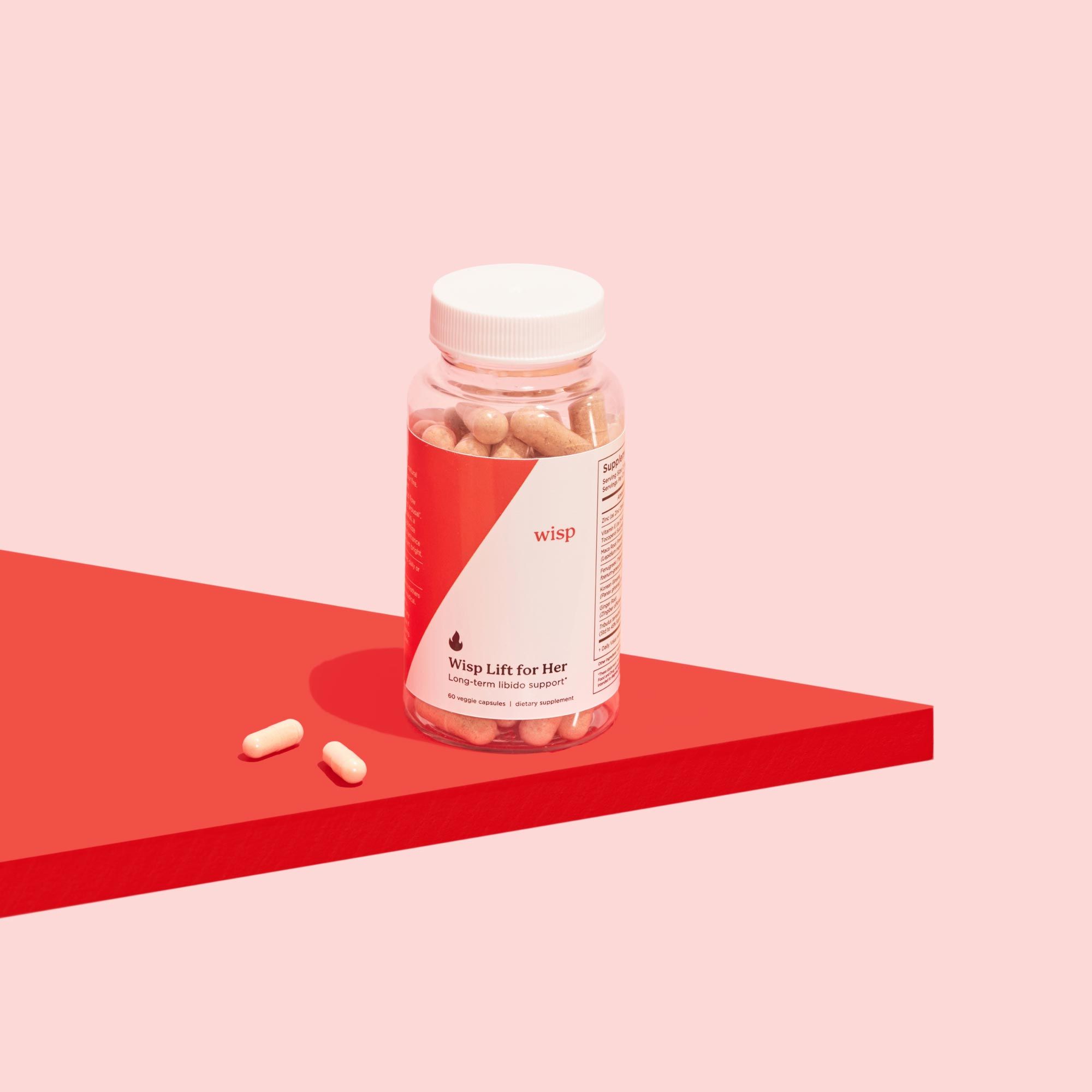 Wisp Lift Libido Supplements for Her with two pills beside the bottle on a red surface with a pink background