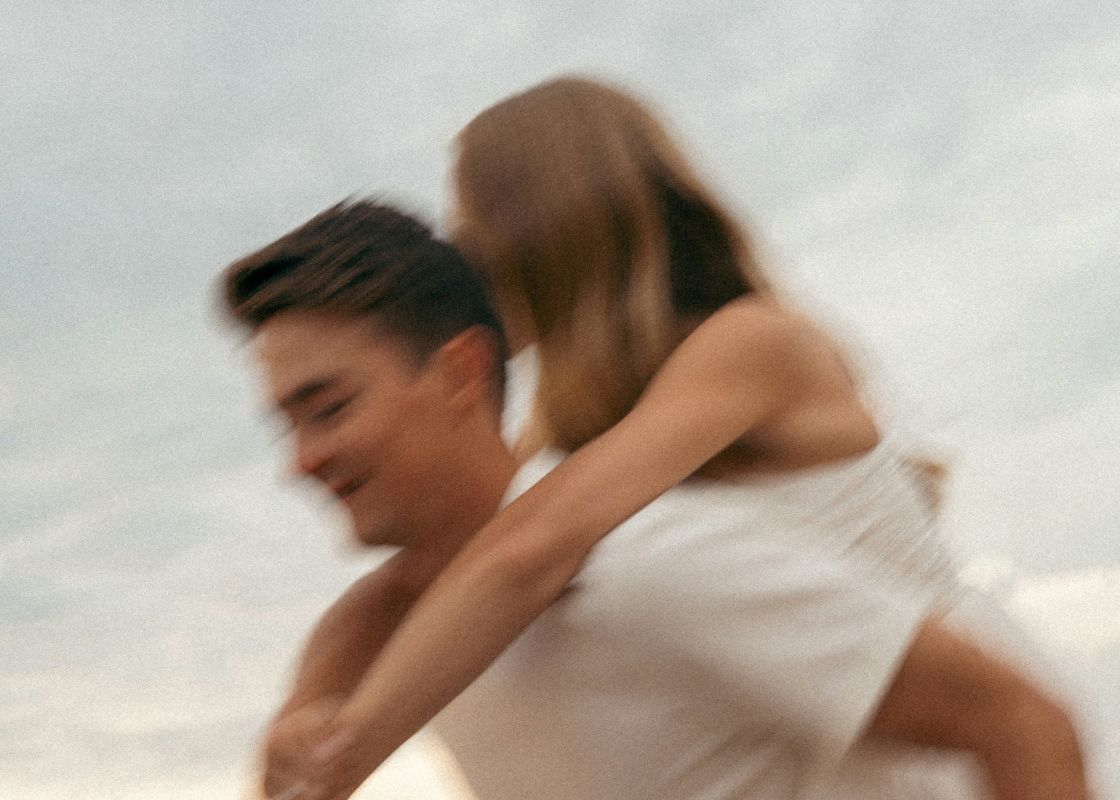 A man carrying a woman on his back outdoors with motion blur