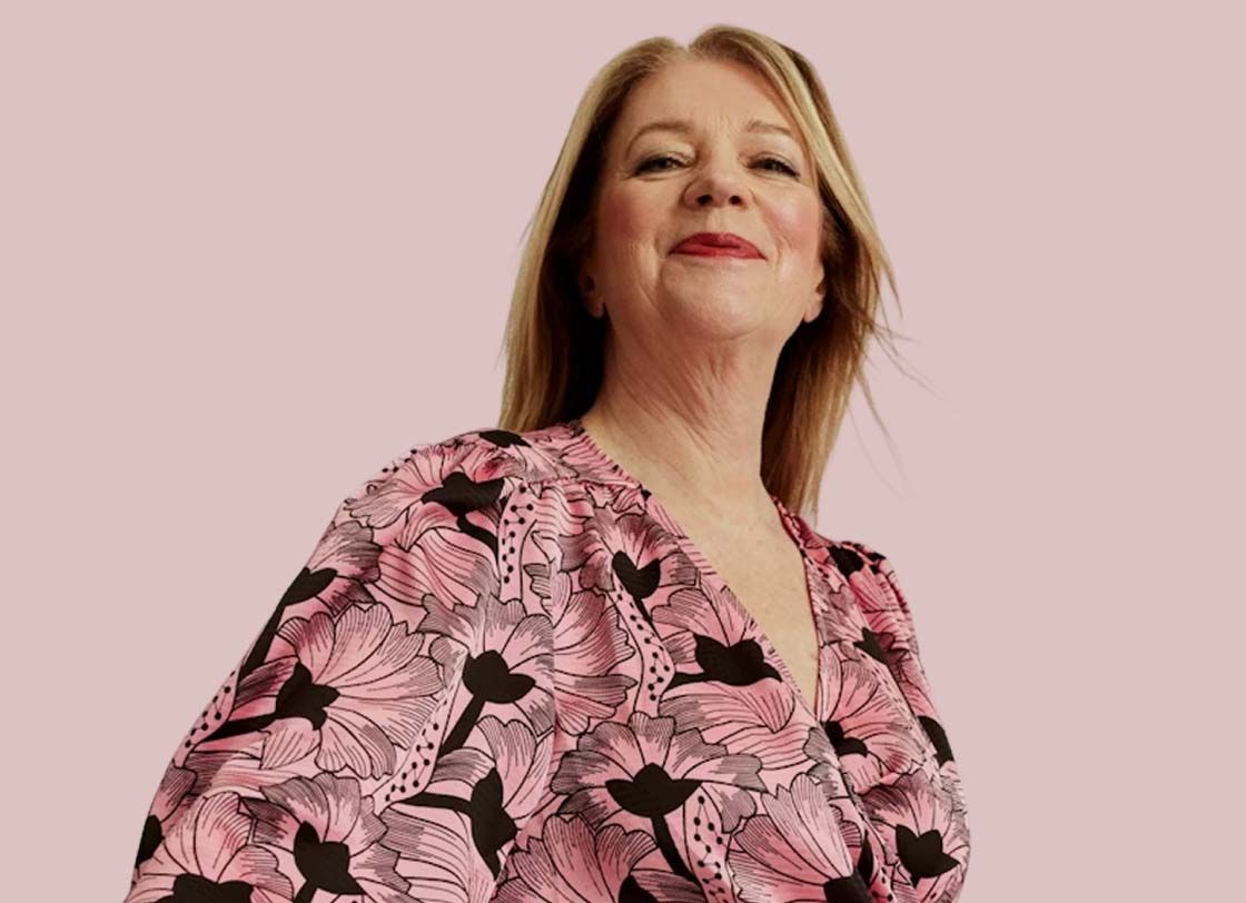 A pretty woman wearing a floral dress looks proud and happy in front of a purple background