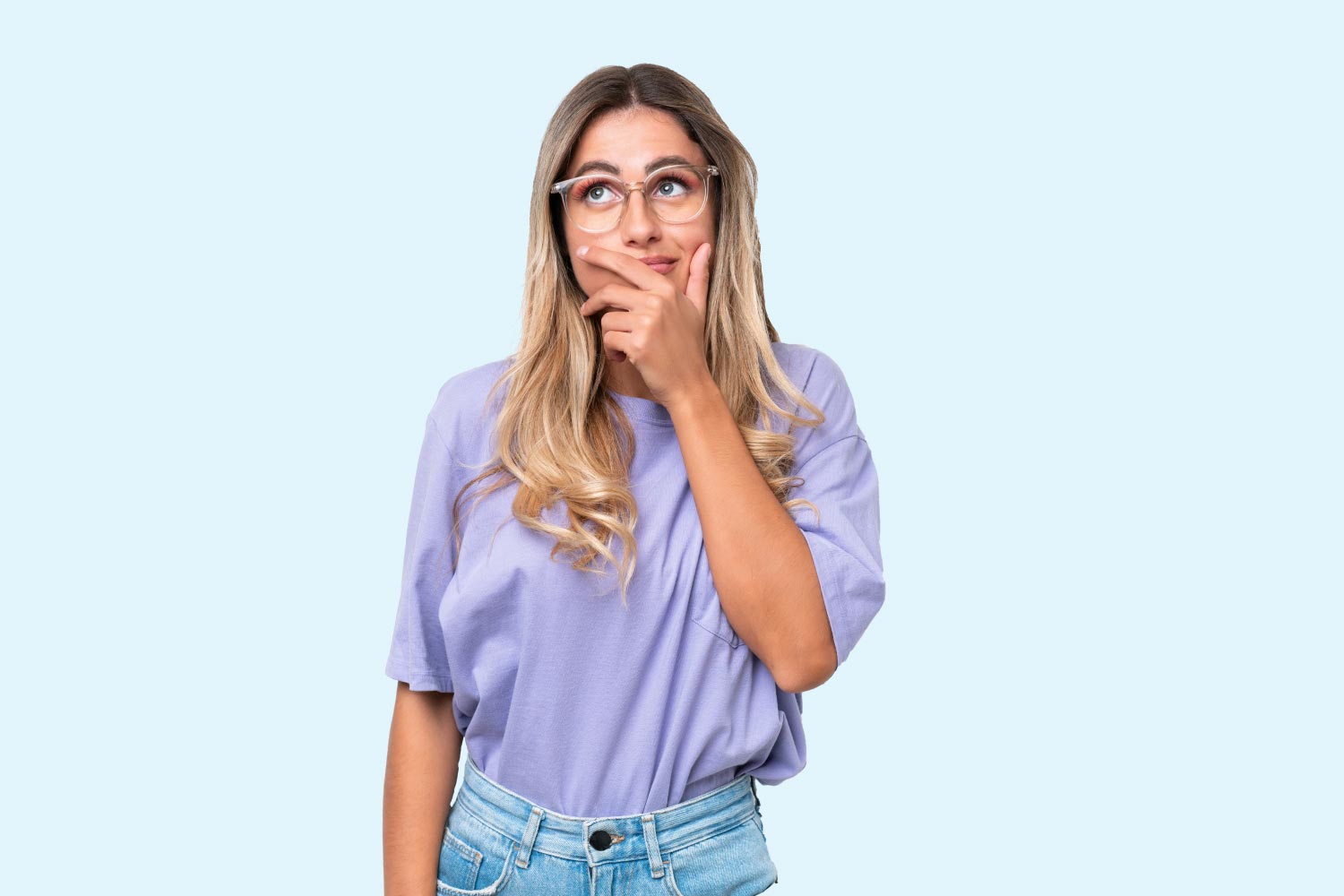 A woman with blonde hair wearing a purple shirt and jeans with a confused look on her face and a light blue background