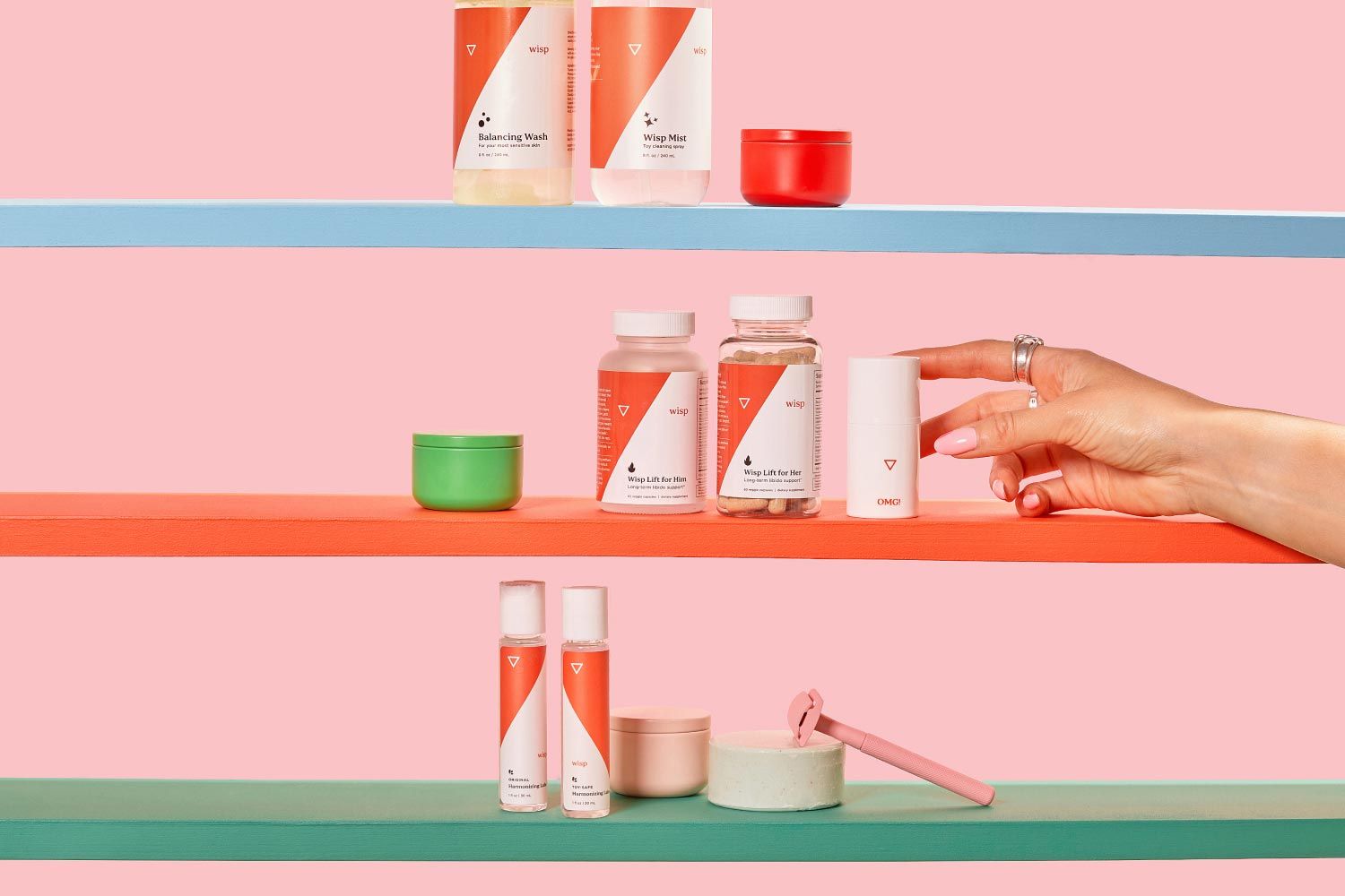 A variety of Wisp products on 3 colorful shelves with miscellaneous containers, a pink razor and a woman's hand reaching for Wisp OMG Cream in front of a pink background