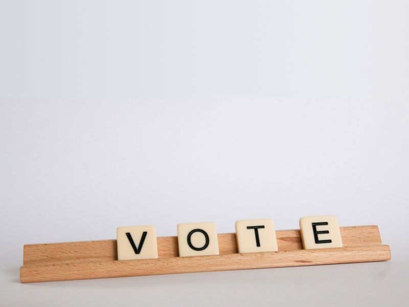 Scrabble tiles spelling out VOTE on a white surface