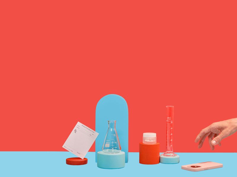 STD treatment meds and testing vials with an rx script and a hand reaching for a mobile phone on a red and light blue background