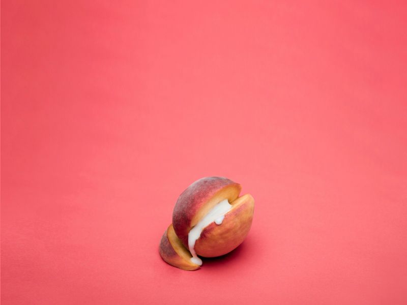 A cut open apricot with a cream substance in the middle on a red background