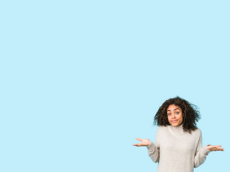 A woman wearing a grey sweater is shrugging in front of a light blue background