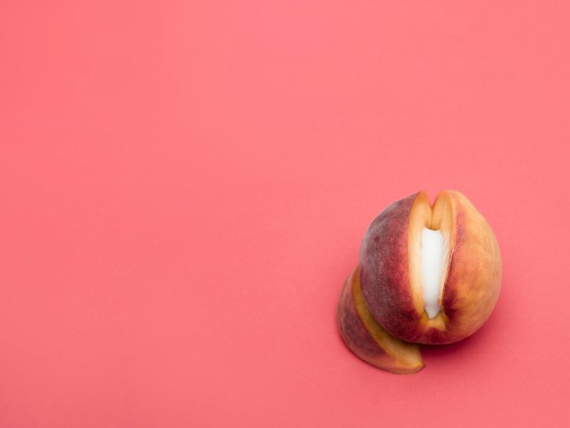 A cut open apricot with a cream substance in the middle on a red background