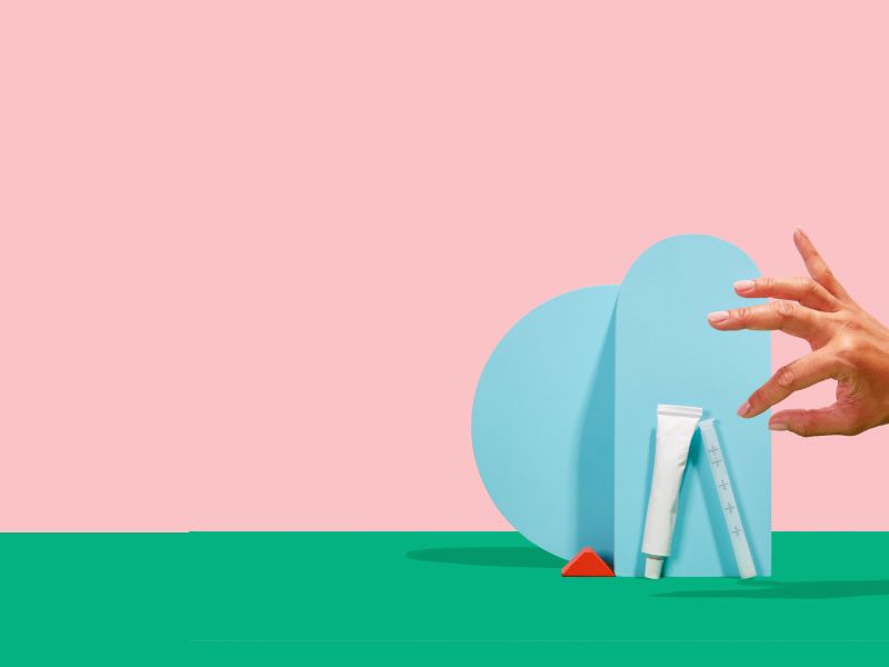 hand reaching out to grab wisp vaginal dryness products in front of blue geometric shapes
