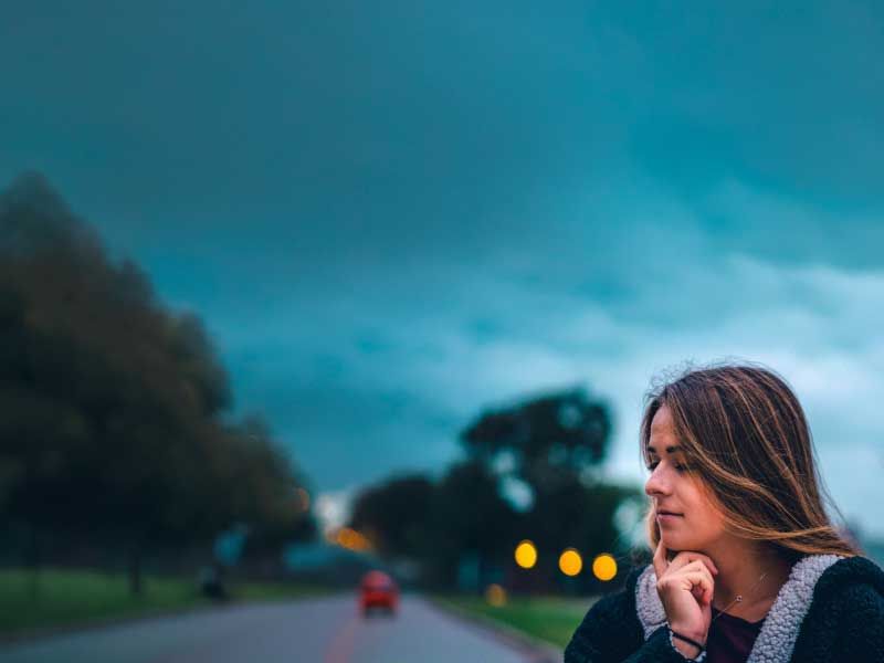 A woman looking contemplative while outside with stormy weather