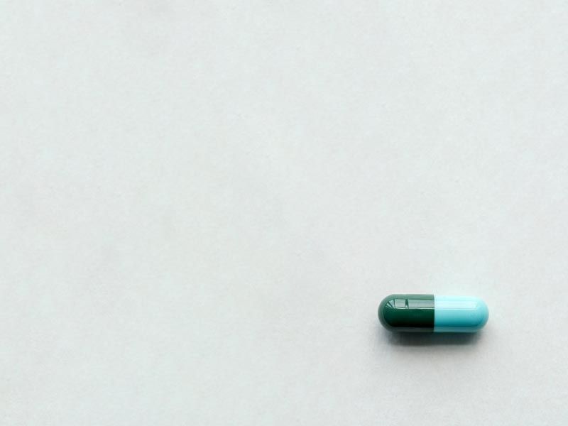 A green and blue capsule on a grey surface