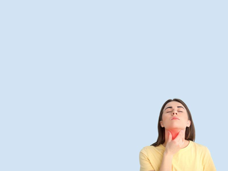 A woman wearing a yellow shirt has her hand on her throat in front of a light blue background