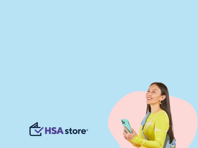 A woman wearing a bright green sweater, orange pants and a light blue backpack is smiling while holding a mobile phone