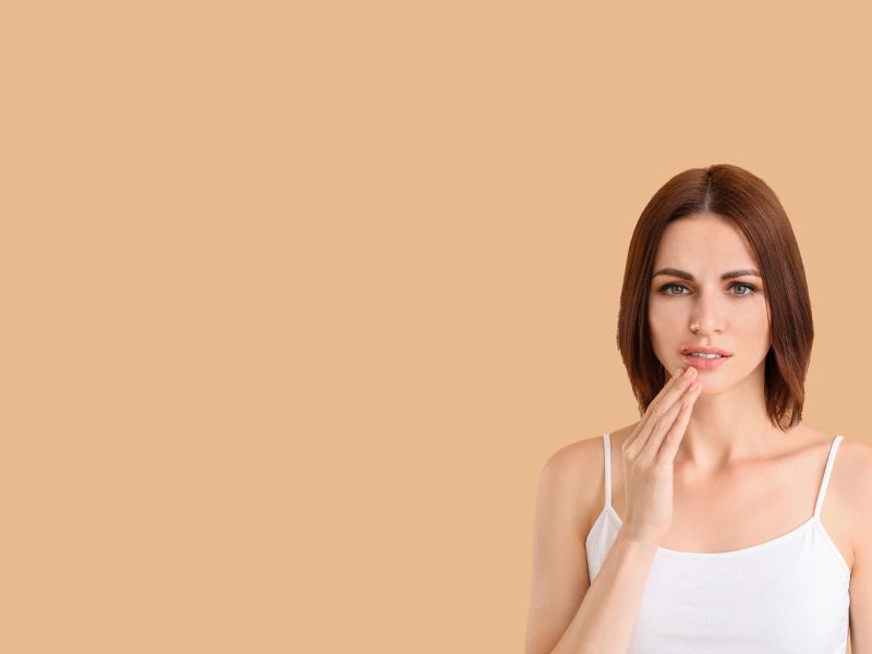 a woman touching a cold sore on her lip