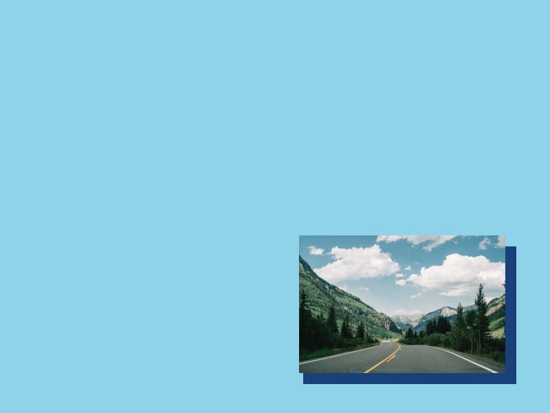 Image of a deserted road in a forest with a partly cloudy sky