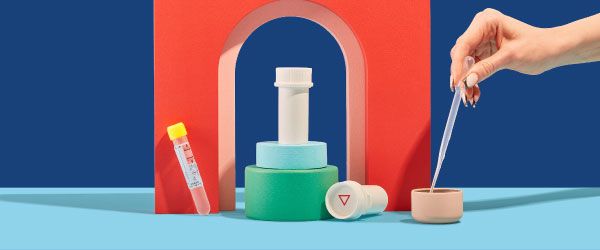 Wisp pill vials and test tubes are balanced on colorful abstract shapes on a blue surface