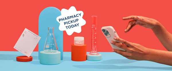Wisp glass pill jar, test tubes, and a prescription script are balanced on colorful abstract shapes on a blue surface with a red background