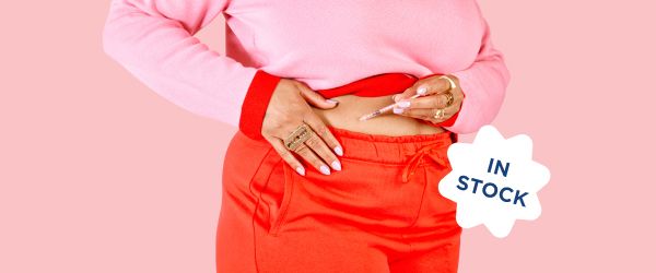 A woman wearing red shorts and a pink sweater injects GLP-1 weight loss medication to her stomach