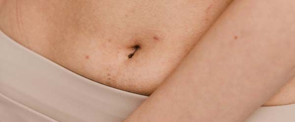 A close up of a woman's midsection with a cream background