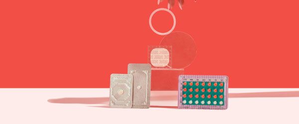 2 Emergency Contraception packets and a birth control packet, ring, and patch are balanced on a clear block on a pink surface with a red background
