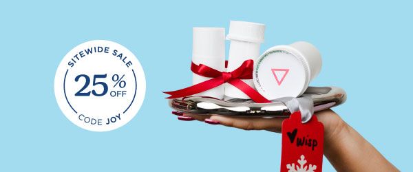 A woman's hand holding a silver tray with multiple Wisp pill vials with a red ribbon around them in front of a light blue background