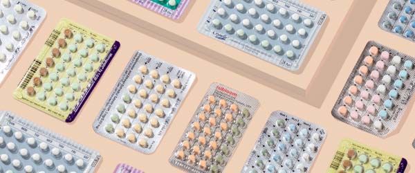 Various birth control pill packets on a cream background