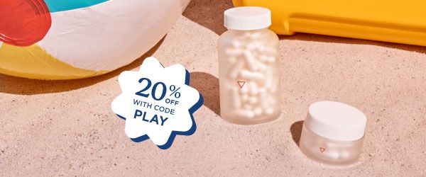 Wisp glass pill jars sitting on beach sand next to a beach ball
