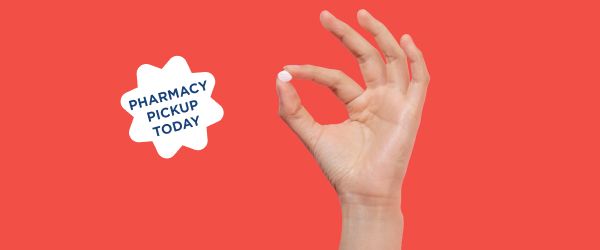 Hand holding fluconazole pill for same-day yeast infection treatment on a red background