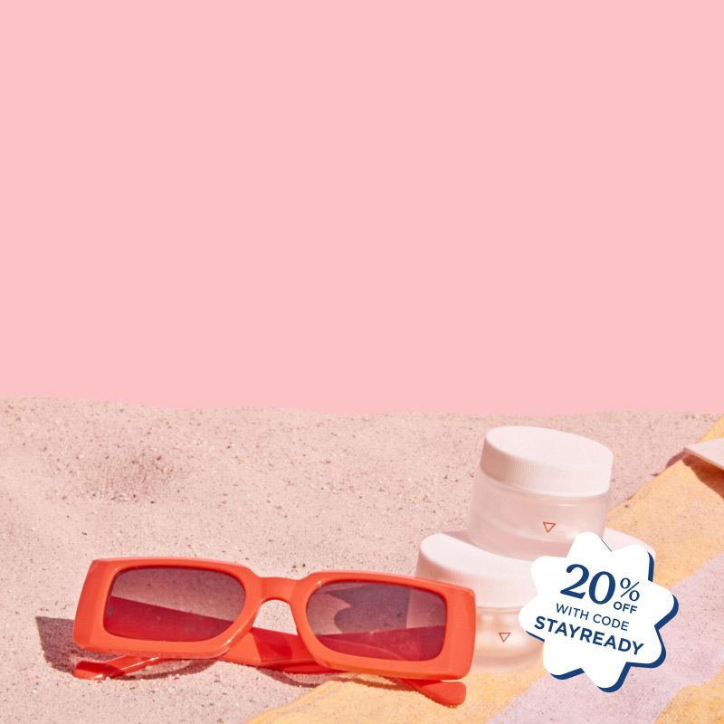 Red sunglasses and 3 Wisp pill jars stacked on a yellow and pink striped beach towel