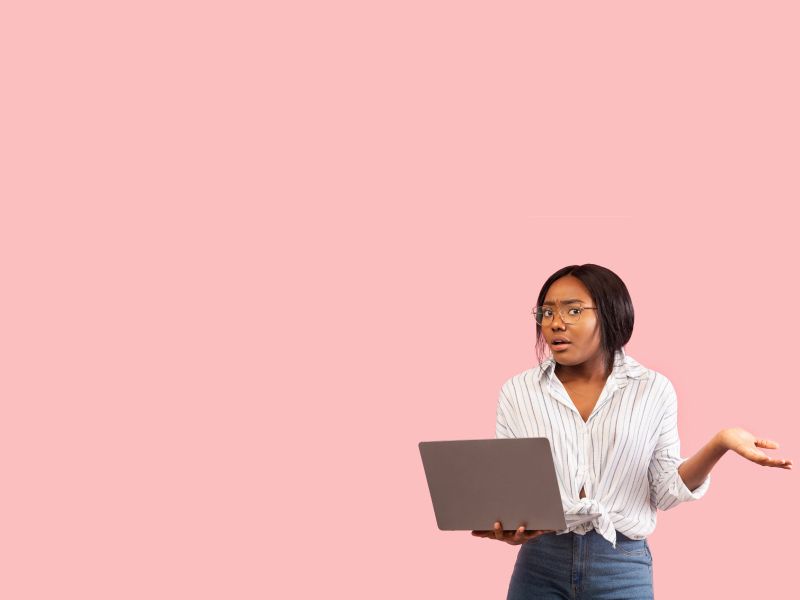 Female holding a laptop and looking confused with a pink background