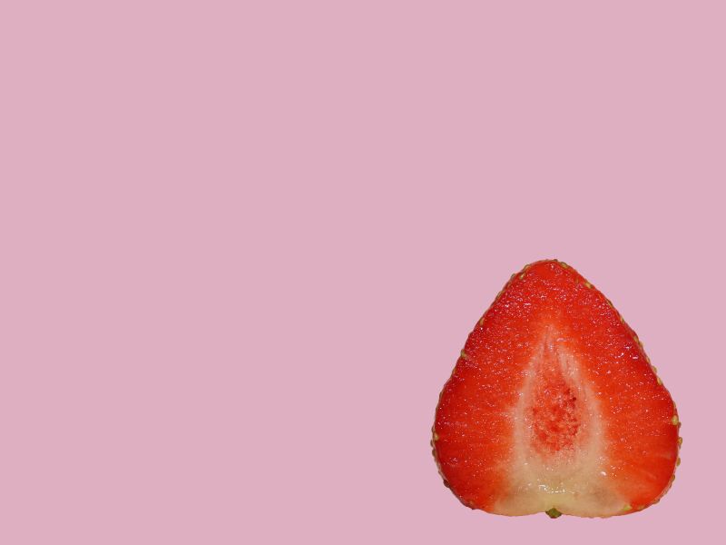 A cut open vulva shaped strawberry with a purple background