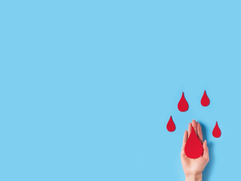 A hand with blood drop cutouts on a light blue surface