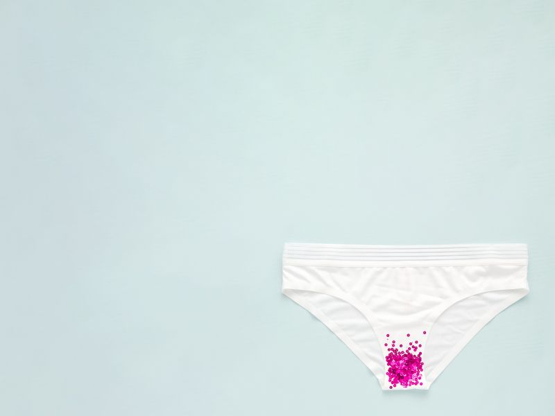 A pair of white underwear with pink glitter on a green background