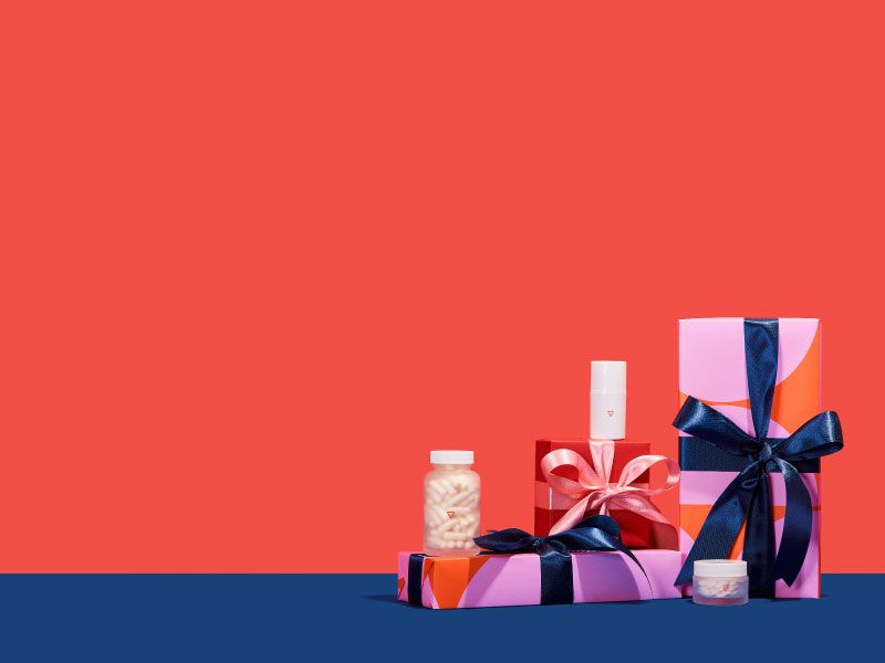 Colorful gift-wrapped boxes with various Wisp products are sitting on a dark blue surface with a red background