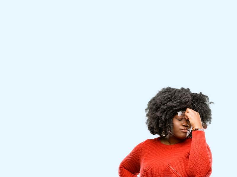 A woman wearing a red sweater is pinching the bridge of her nose in discomfort