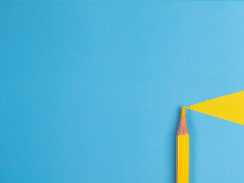 A yellow colored pencil on a blue and yellow surface