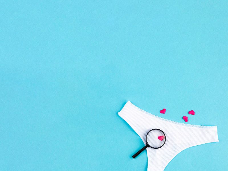 A pair of white underwear with a magnifying glass on them over a light blue surface