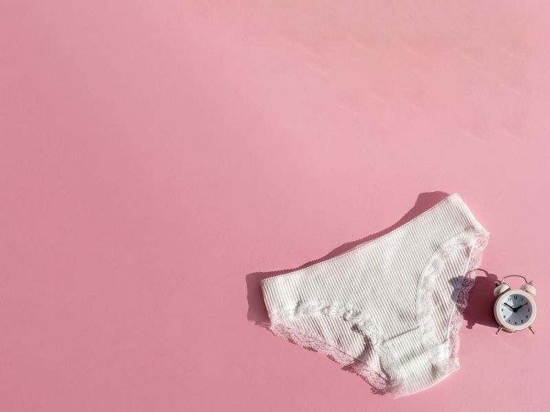 White underwear with a white alarm clock on a pink background