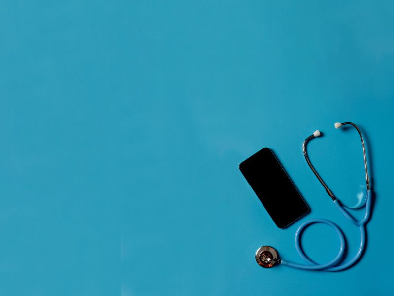 A stethoscope and a mobile phone laying on a teal surface