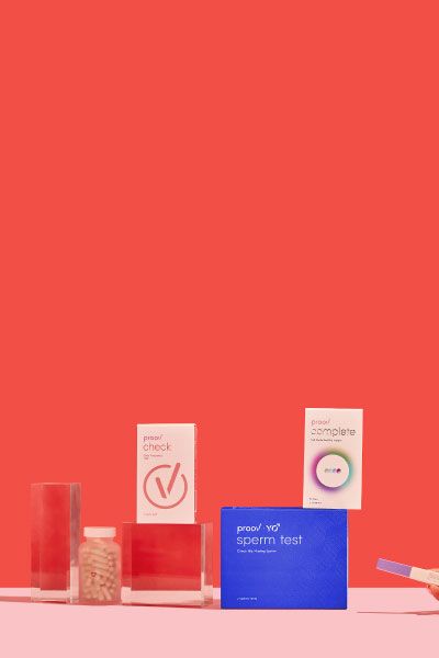Proov Complete and Hers & His Testing kits next to Wisp Prenatal Vitamins and Pregnancy test on a pink surface with a red background