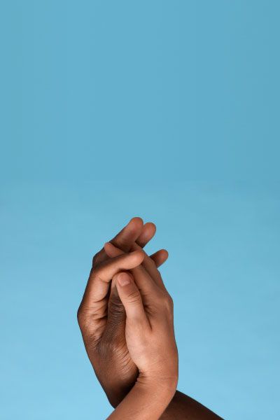 Two hands embracing in front of a blue background
