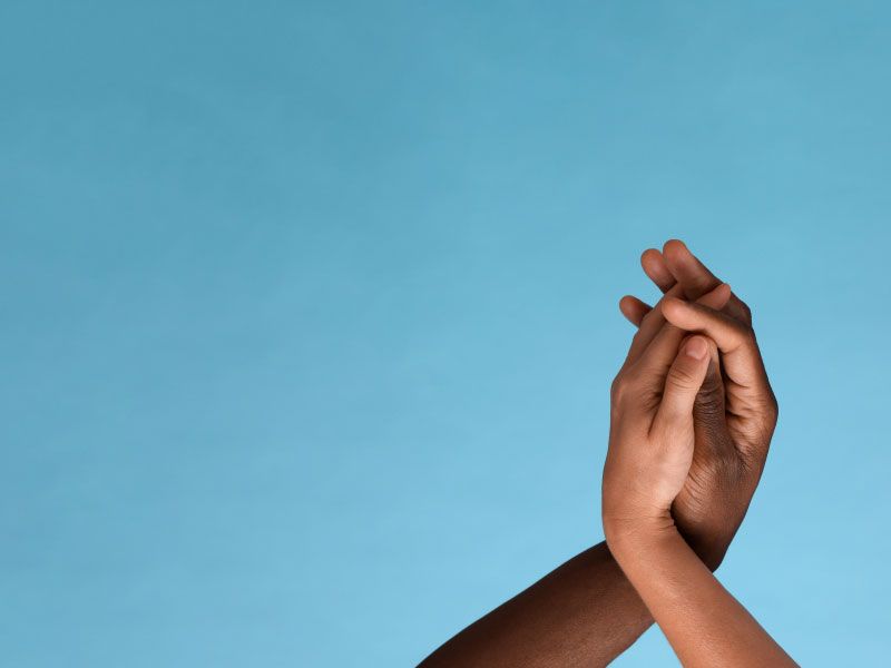 Two hands embracing in front of a blue background