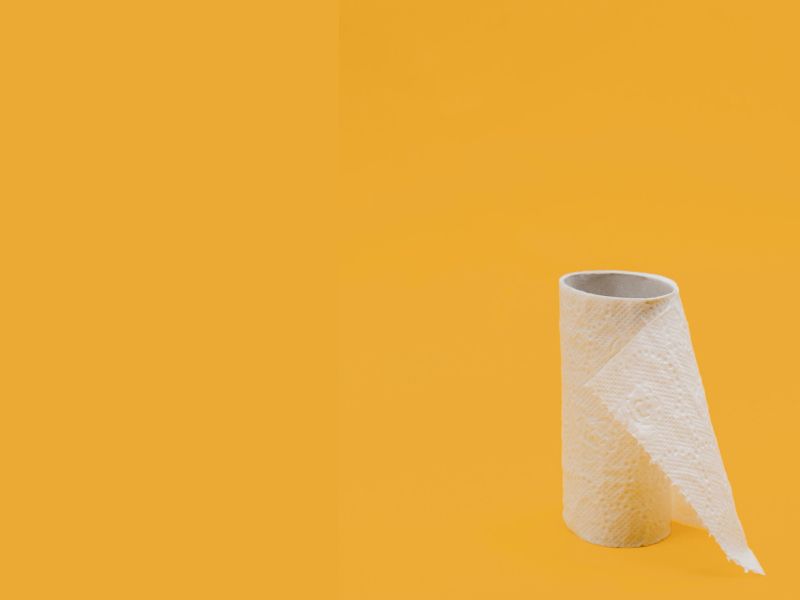 An almost empty toilet roll sitting on a yellow surface