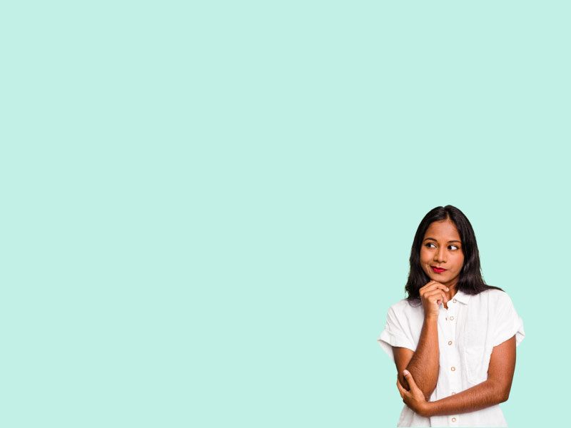 A woman wearing a white button down shirt is looking confused in front of a light green background