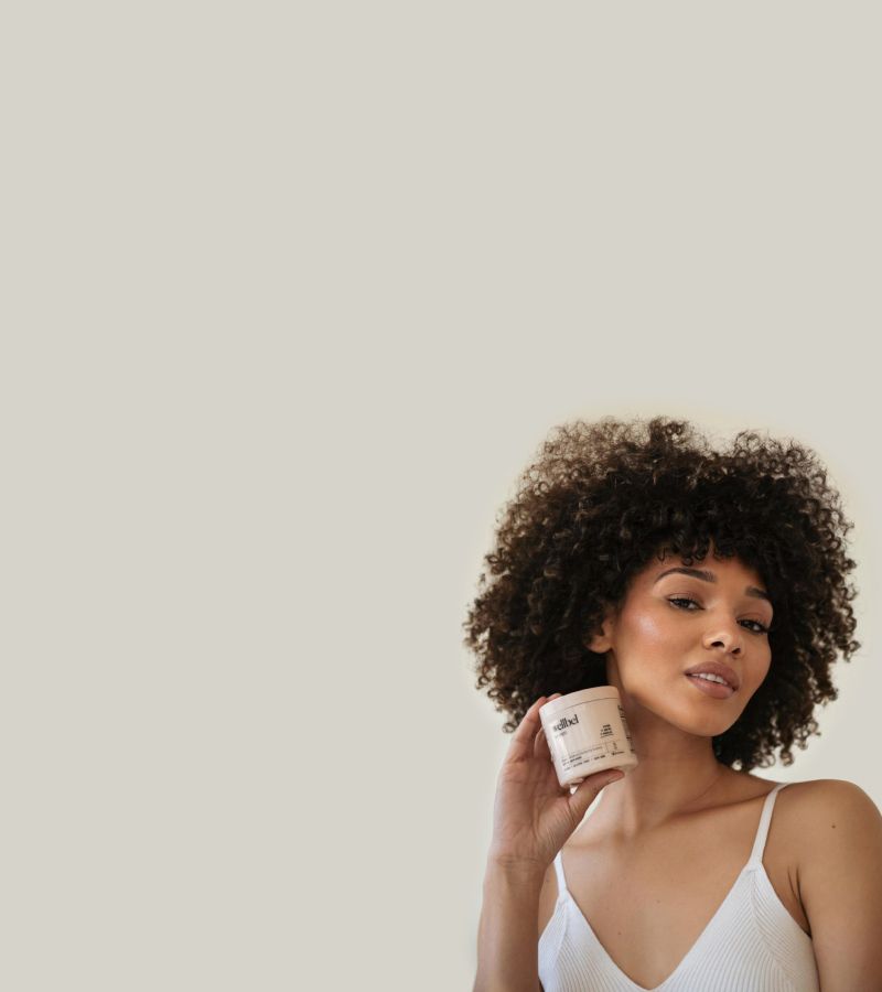 A woman holding a bottle of Wellbel hair supplements
